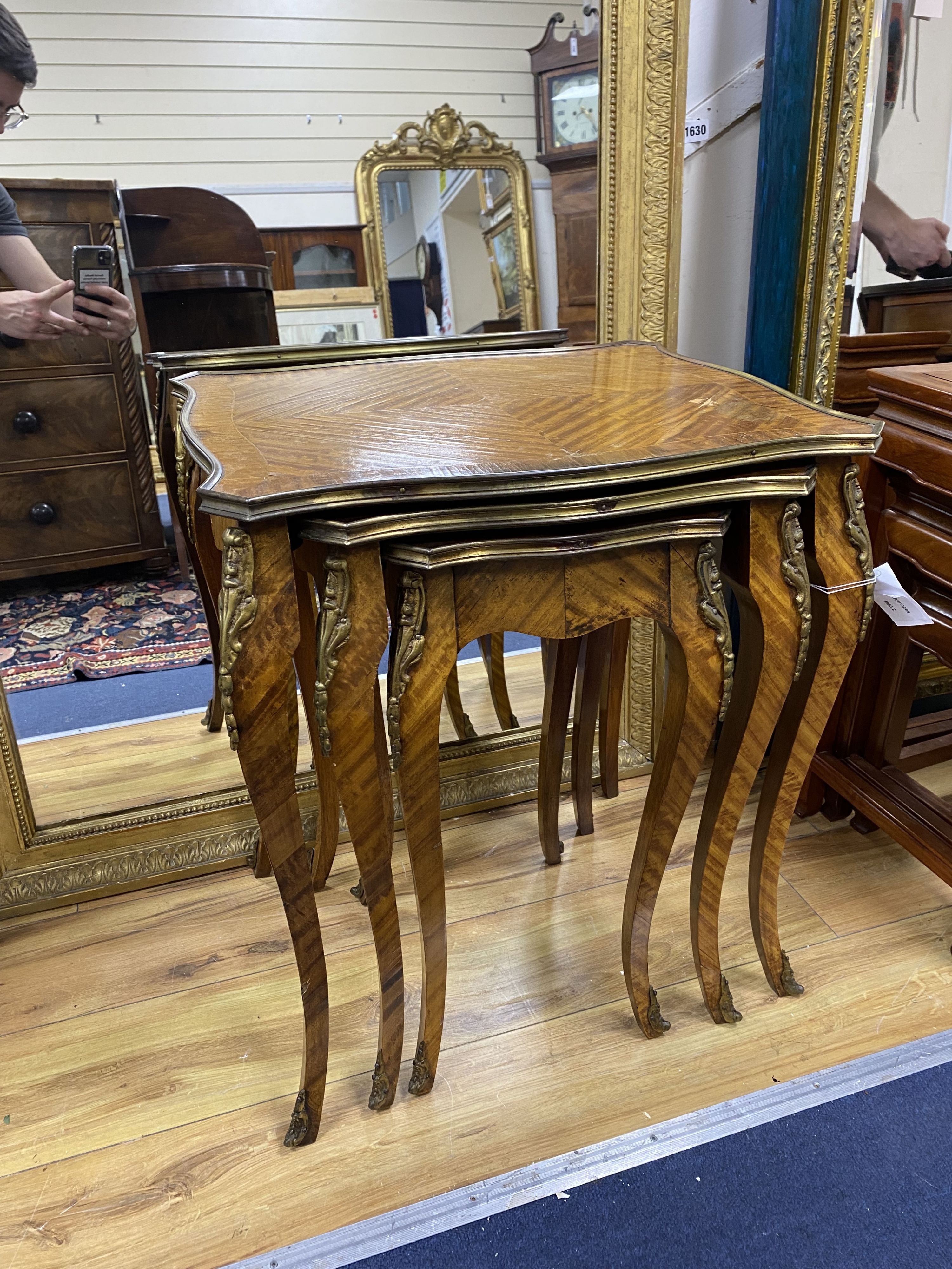 A nest of three Louis XV style ormolu mounted banded kingwood tables, with serpentine sides, on cabriole legs, width 51cm, depth 41cm, height 59cm